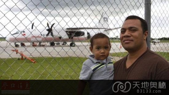 努库阿洛法居民抱着孩子在富阿阿莫图机场，身后是中国赠送的新舟60飞机。
