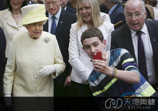 当地时间2014年6月24日，北爱尔兰贝尔法斯特，伊丽莎白二世女王视察圣乔治市场，一名大男孩竟试图举起手机与女王自拍。（来源：东方IC）
