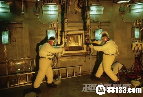 两名技术人员在整修机械臂期间身穿加压防污套装。他们所在的位置是一个“热室”，即高放射性物质工作屏蔽室